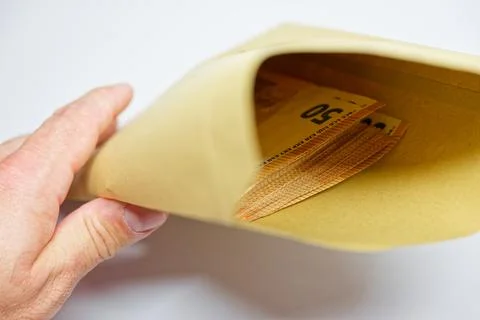 Cash stack partly inside envelope held in a careful hand pose Stock Photos