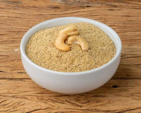 Cashew nut flour in a bowl over wooden table. Gluten free flour Stock Photos