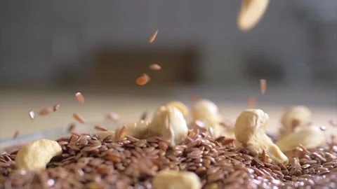 Cashew nuts fall into flax seeds Stock Footage