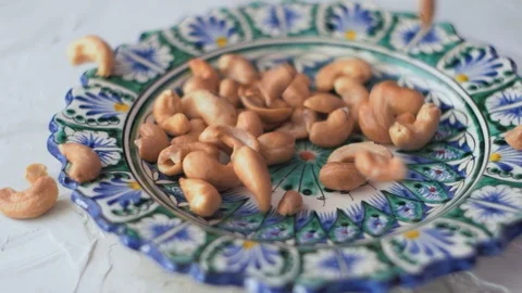 Cashew nuts falling on the oriental plate with blue and white pattern Stock Footage 128301769