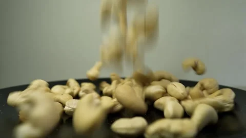 Cashew nuts scattered on a black surface with a plain background Stock Footage 318578401