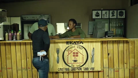 Cashier explaining the menu to a customer over the counter Stock Footage 254797912