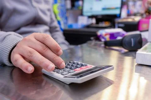 Cashier hands while calculating with barcode scanner and cashier drawer in .. Stock Photos