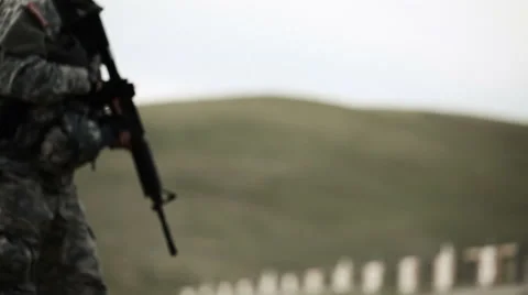 Casing flies at the camera as soldiers fire from kneeling stance Stock Footage 52700176