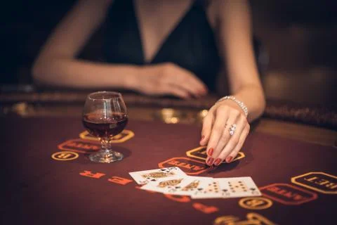 Casino, a girl playing cards. On the table is cognac, in the spotlight is a h Stock Photos