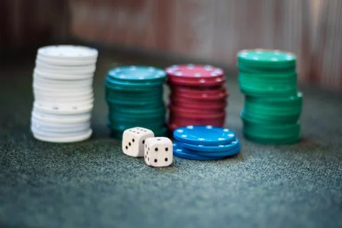 Casino poker chips stack dice on green felt background. Stock Photos