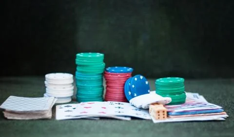 Casino poker chips stack with playing cards, dice and money on green felt bac Stock Photos