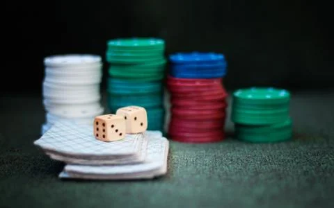 Casino poker chips stack with playing cards, dice on green felt background. Stock Photos
