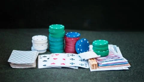 Casino poker chips stack with playing cards, dice and money on green felt bac Stock Photos