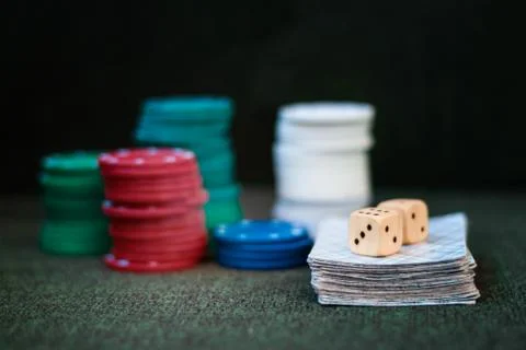 Casino poker chips stack with playing cards, dice on green felt background. Stock Photos