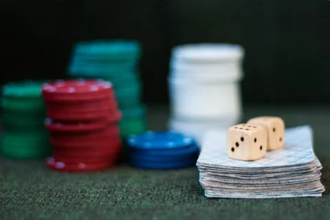 Casino poker chips stack with playing cards, dice on green felt background. Stock Photos