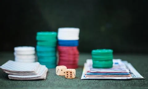 Casino poker chips stack with playing cards, dice and money on green felt bac Stock Photos
