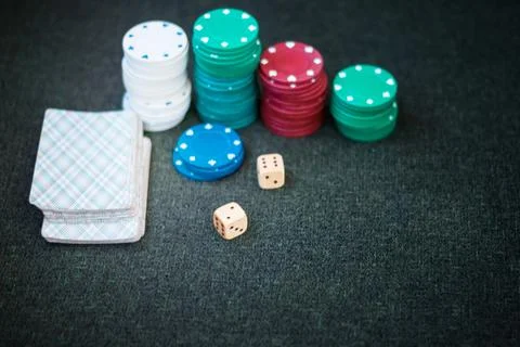 Casino poker chips stack with playing cards, dice on green felt background. Stock Photos