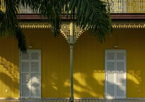 Cast-iron column beneath a palm frond flanked by two shuttered doors on the.. Stock-Fotos
