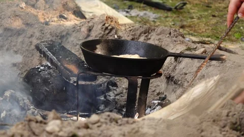 Cast-iron frying pan with meat fillet stands at street stake. Person is tryin Stock Footage 212954071