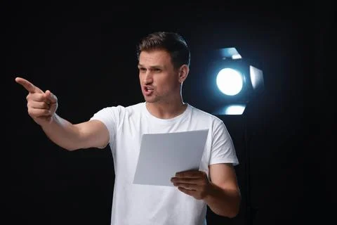 Casting call. Emotional man with script performing on black background Stock Photos