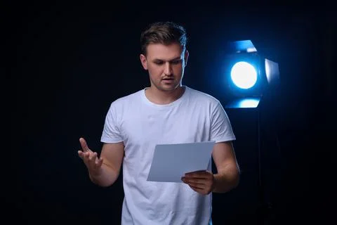 Casting call. Emotional man with script performing on black background Stock Photos