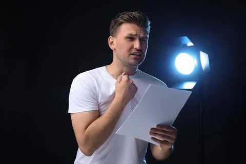 Casting call. Emotional man with script performing on black background Stock Photos