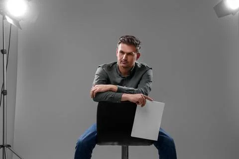Casting call. Man with script sitting on chair against grey background in s.. Stock Photos