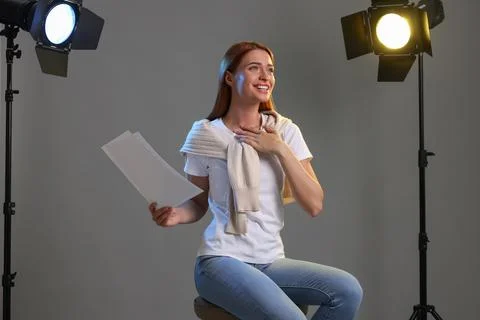 Casting call. Young woman with script performing on grey background in studio Stock Photos