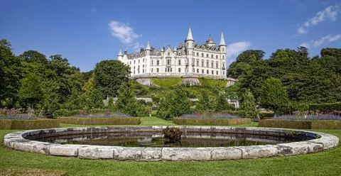 A castle with a clock tower in front of a building Stock Photos