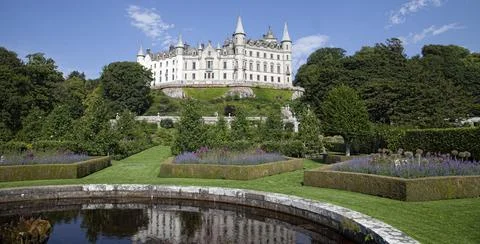 A castle with a clock tower in front of a building Foto stock