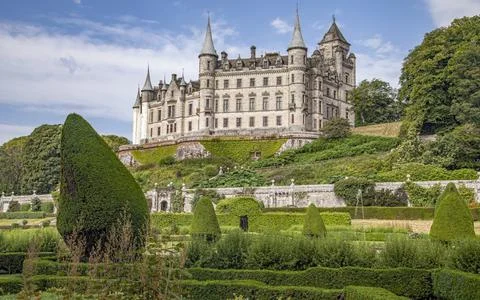 A castle with a clock tower in front of a building Stock Photos