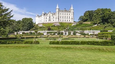 A castle with a clock tower in front of a building Stock Photos