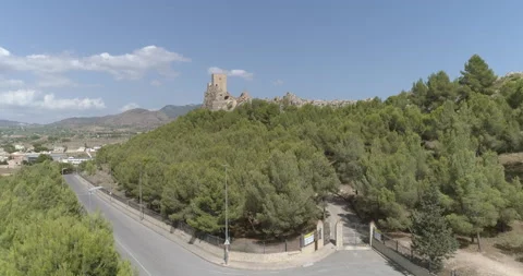 Castle on a rocky cliff surrounded by forests and above a medieval village seen Stock Footage 209988248