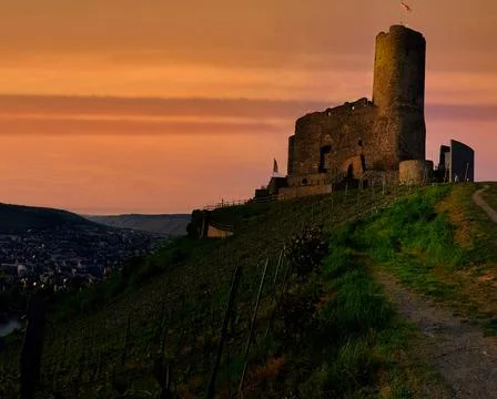 Castle stands on a hill at sunset overlooking a valley and a village in the.. Stock Photos