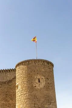 Castle tower built with stone blocks and the Spanish flag flying at the top.. Stock-Fotos