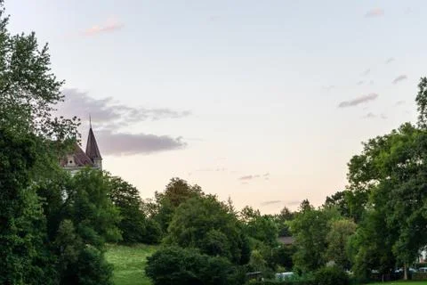 Castle tower can be seen through trees in sunset evening blue hour Stock Photos