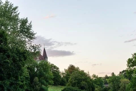 Castle tower can be seen through trees in sunset evening blue hour Stock Photos