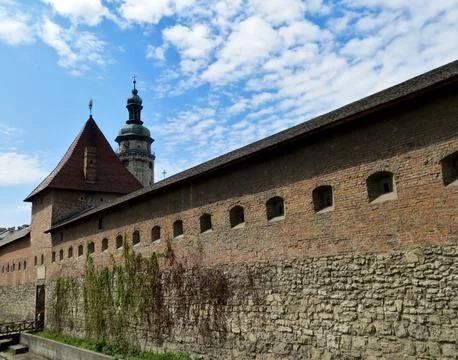 Castle wall with a tower on a background of blue sky with clouds Stock Photos