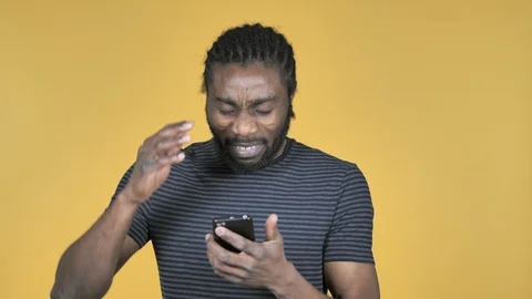 Casual African Man in Shock while Using Smartphone Isolated on Yellow Background Stock Footage 99215501