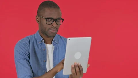 Casual African Man Using Digital Tablet on Red Background Stock Footage 295165553