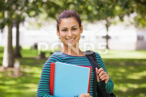 Casual cheerful student looking at camera holding books Stock Photos