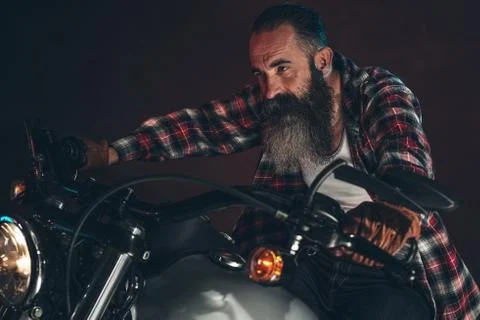 Casual cool long beard man on motorcycle at night. Stock Photos