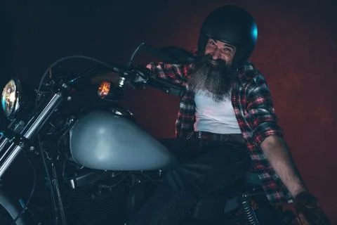 Casual cool long beard man with helmet riding motorcycle at night. Stock Photos