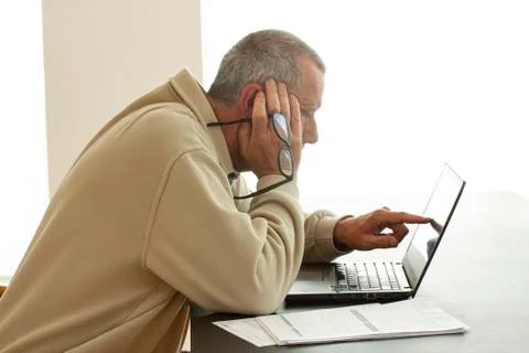Casual dressed man pointing at computer screen and holding a pair of glasses Stock Photos