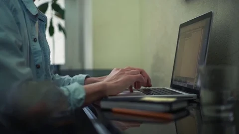 Casual dressed young man using laptop making notes in notepad at home Stock Footage 82928019