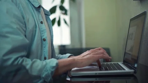 Casual dressed young man using laptop drinking coffie in office Stock Footage 82930262