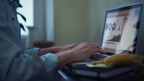 Casual dressed young man using laptop making notes in notepad at home Stock Footage 82931764
