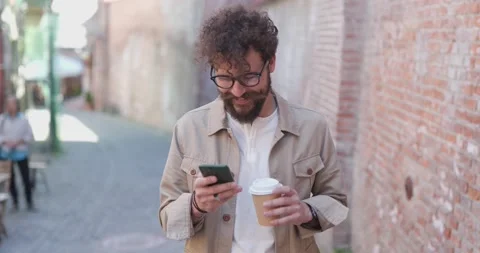Casual guy drinking coffee, wearing eyeglasses, texting on his phone in the Stock Footage 158675799