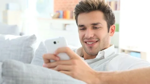 Casual guy using smartphone, relaxing in couch Stock Footage 44098170