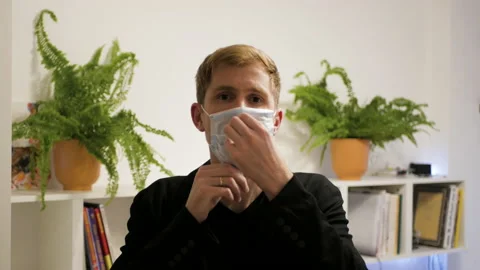 Casual man puts on surgical mask COVID-19 Coronavirus pandemic outbreak. Stock Footage