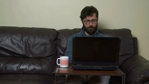 Casual Man Sitting on Comfortable Sofa and Working on Computer Stock Footage 76522721