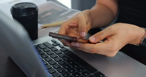 Casual multitasking scene. Individual using phone and laptop at desk with coffee Stock Footage 344731875