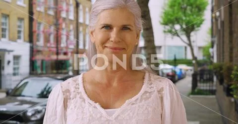 Casual portrait of lovely mature woman standing on residential street in London Stock Photos