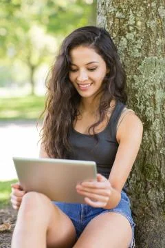Casual smiling brunette sitting using tablet 스톡 사진